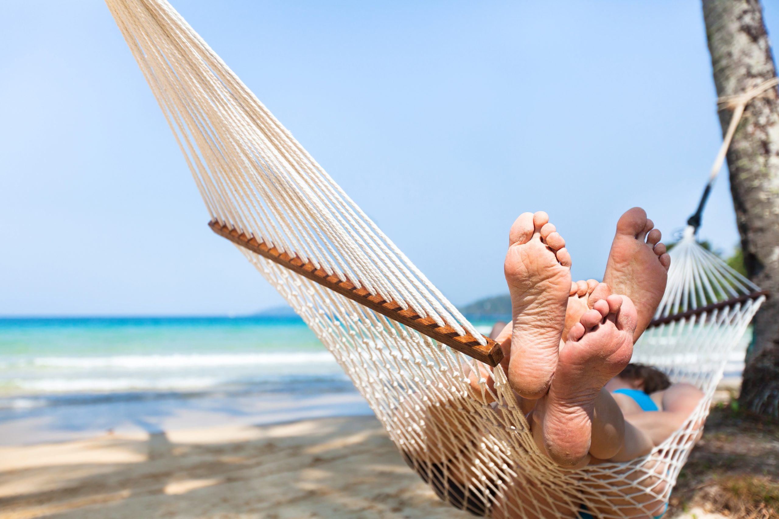 happy couple family in hammock on tropical paradise beach, island holidays, closeup of feet